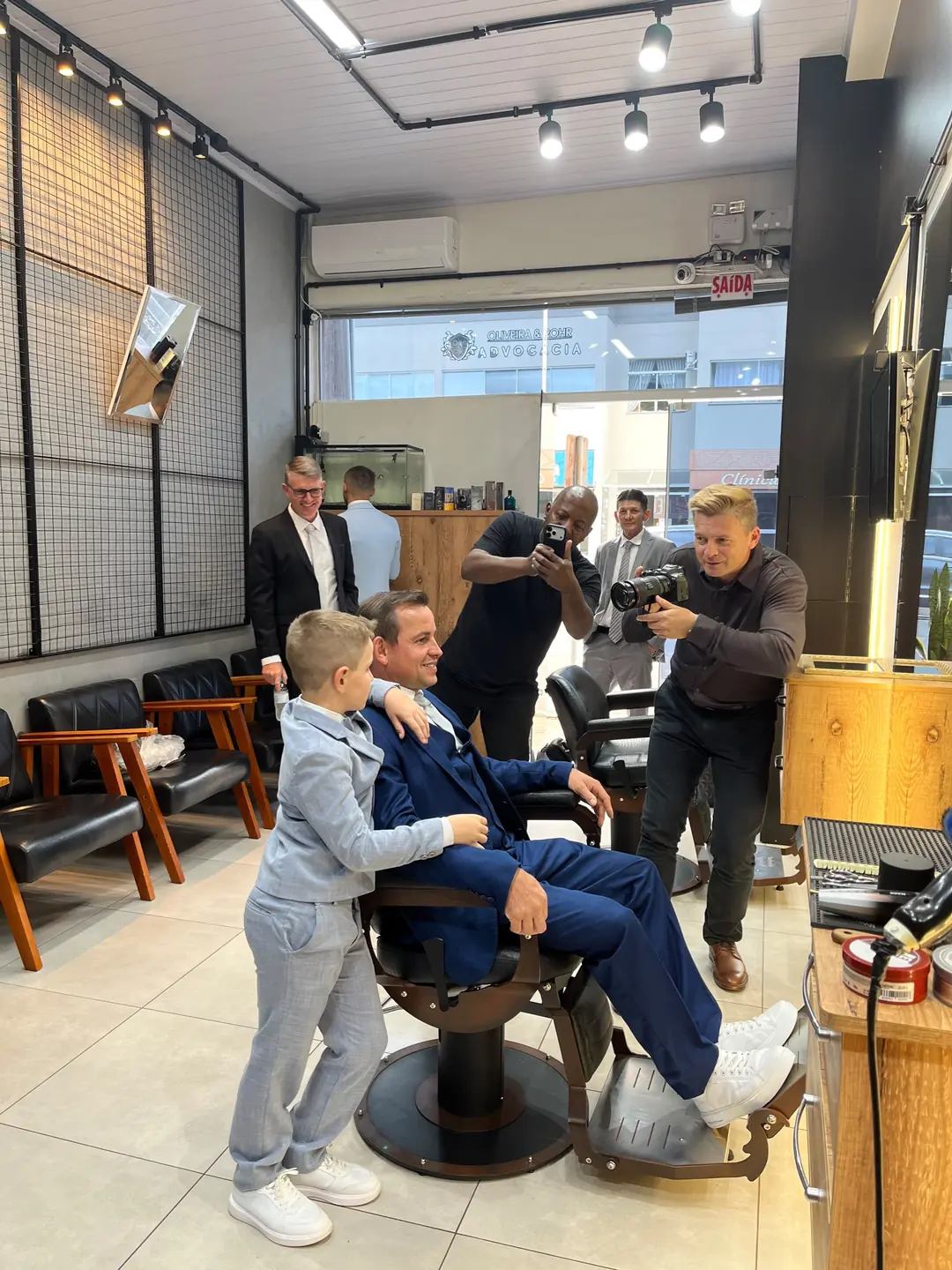 Salão da Barbearia Wolf com área de espera, cadeiras de barbeiro, iluminação em trilho e vitrine para a rua
